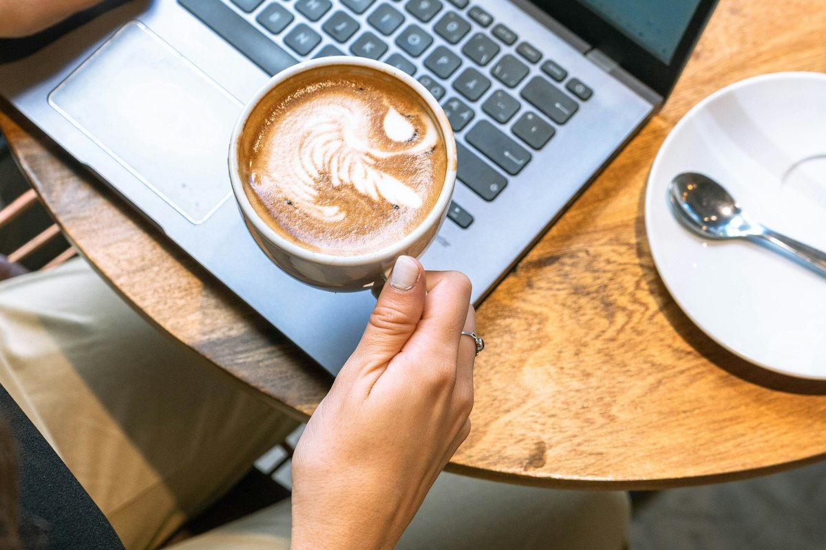 Persona con un café frente a una notebook