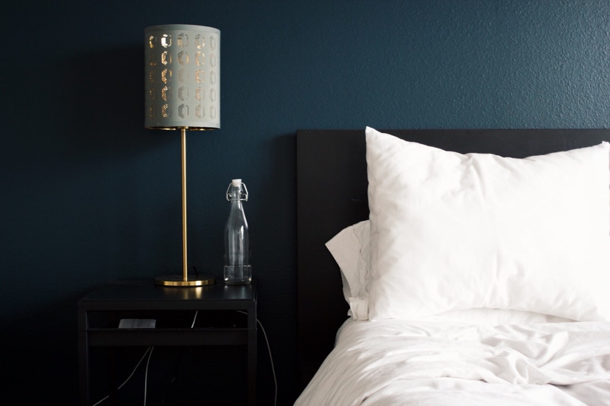 Cama de hotel con cabecera azul y lámpara