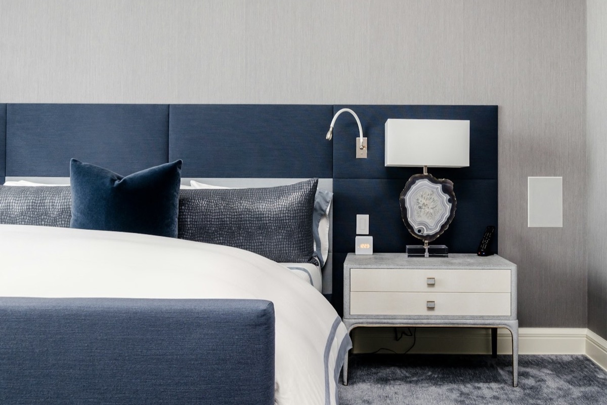 Cama de hotel con almohadas blancas y luz de mesa