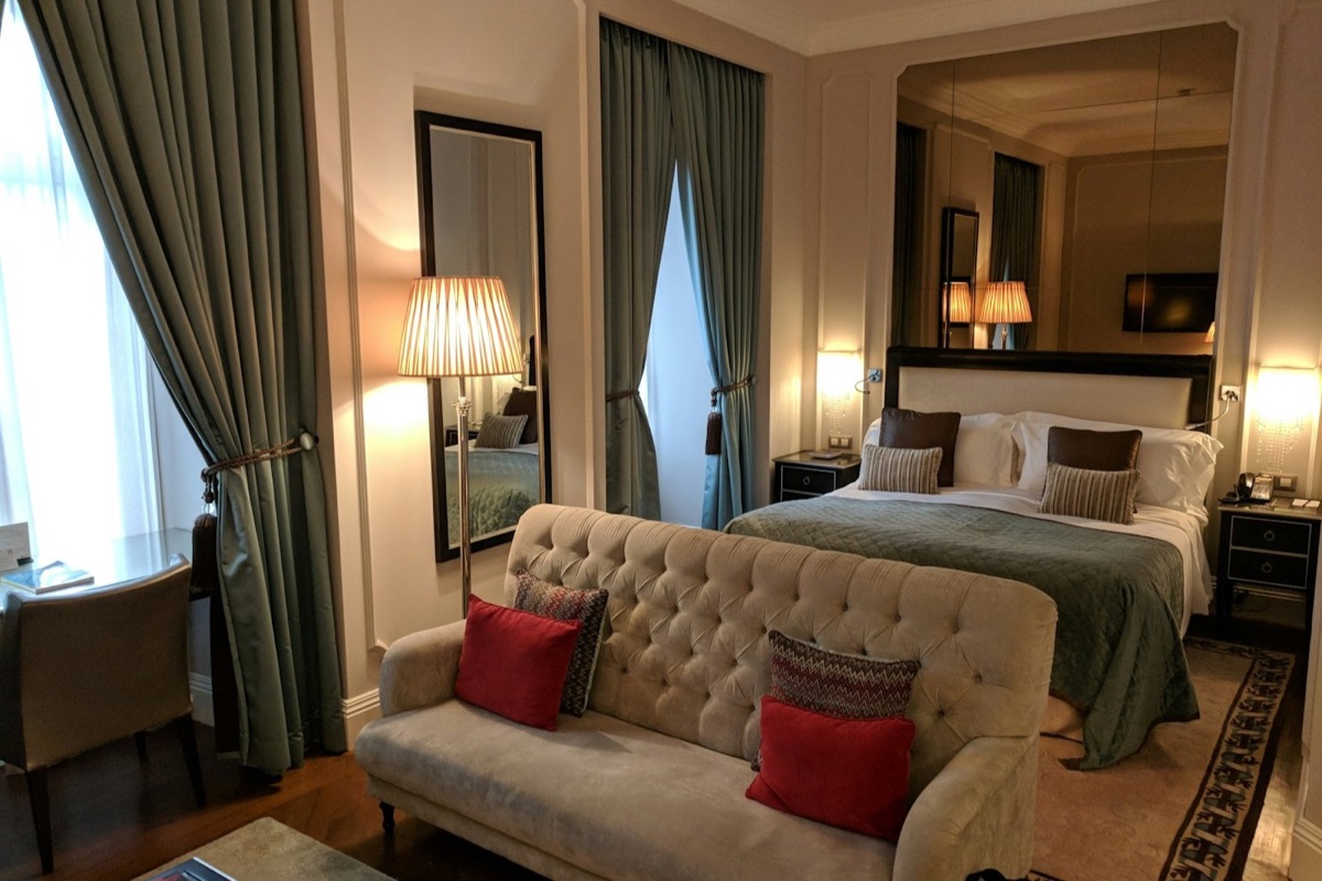 Habitación de hotel con cama, luz natural y sillón
