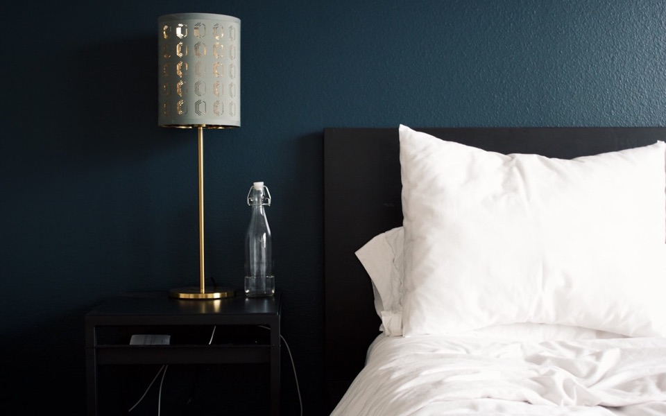 Cama de hotel con cabecera azul y lámpara